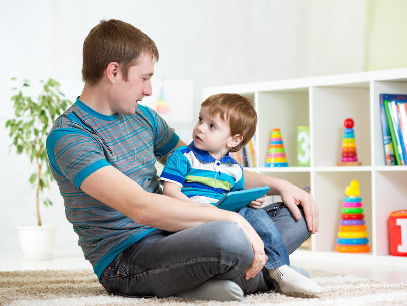 dad-son-kid-play-tablet-computer-indoors-playing-52195166.jpg